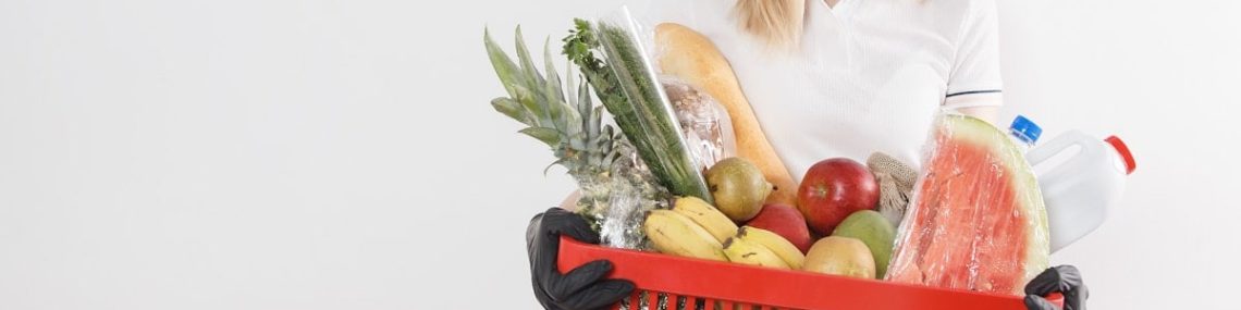 Young woman with goods in basket. The girl made a purchase. Girl holding a basket of groceries. Vegetables