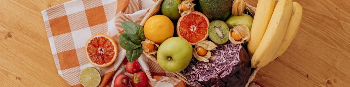 A vibrant flat lay of assorted fresh fruits on a checkered cloth over a wooden surface, perfect for healthy lifestyle concepts.